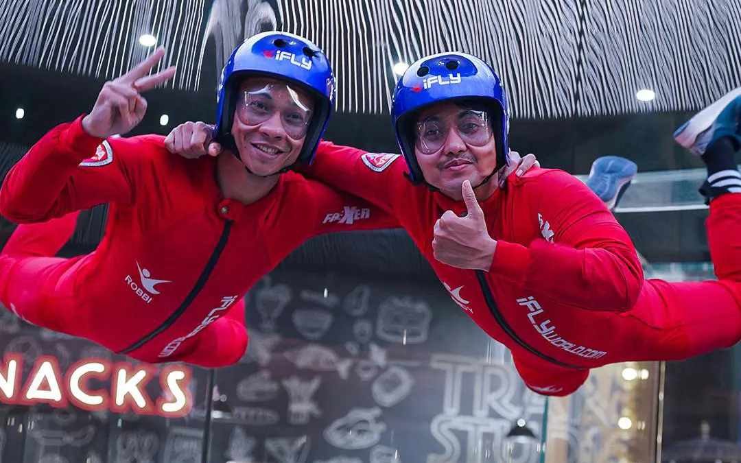 Indoor skydivers in red suits at i-Fly Bali, Indonesia's first indoor skydiving experience.