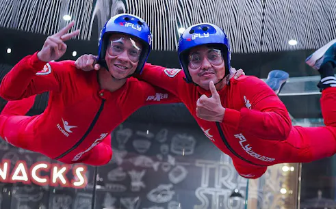Indoor skydivers in red suits at i-Fly Bali, Indonesia's first indoor skydiving experience.