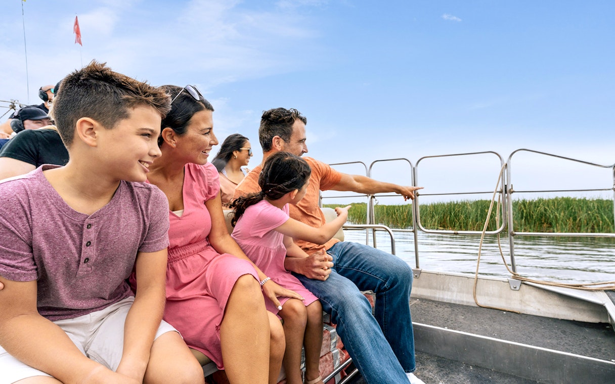 Guests enjoying an airboat tour in the Everglades, surrounded by water and reeds.