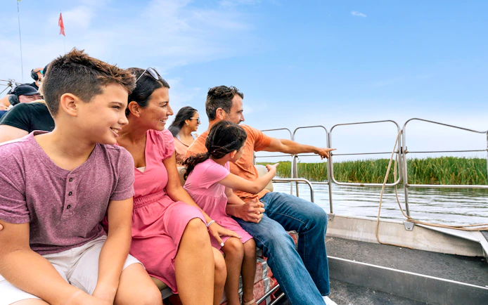Guests enjoying an airboat tour in the Everglades, surrounded by water and reeds.