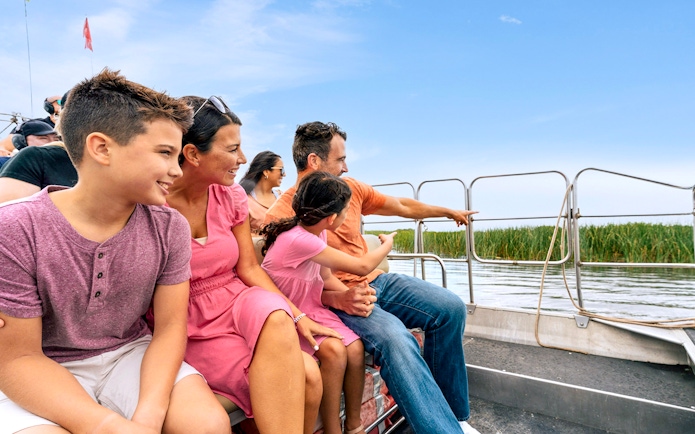Guests enjoying an airboat tour in the Everglades, surrounded by water and reeds.