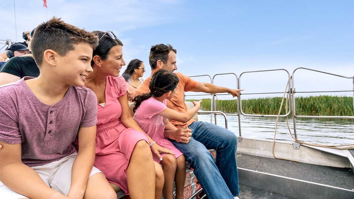 Guests enjoying an airboat tour in the Everglades, surrounded by water and reeds.