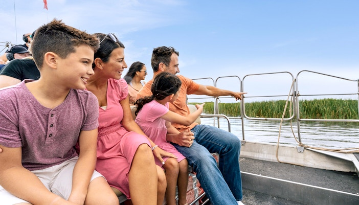 Guests enjoying an airboat tour in the Everglades, surrounded by water and reeds.