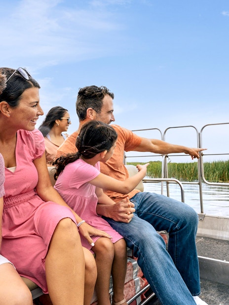Guests enjoying an airboat tour in the Everglades, surrounded by water and reeds.