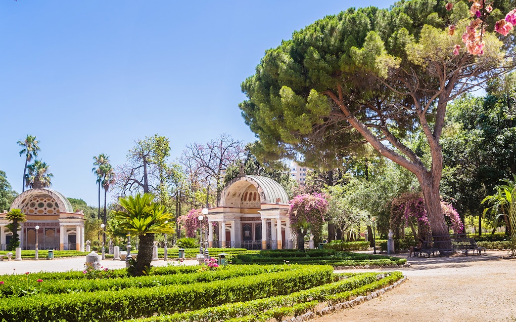 Orto Botanico garden with lush greenery and historic pavilion, Palermo, Italy.