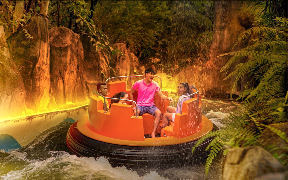 Guests enjoying a raft ride through Grand Canyon river rapids surrounded by lush greenery.