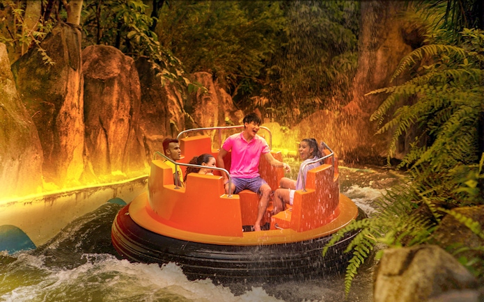 Guests enjoying a raft ride through Grand Canyon river rapids surrounded by lush greenery.