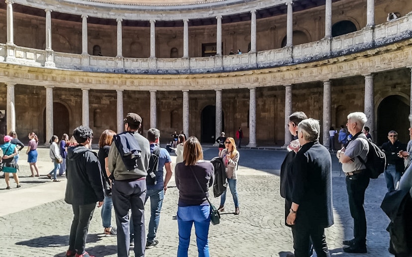 Visitors in the circular courtyard of the Alhambra's Nasrid Palaces during a guided tour.
