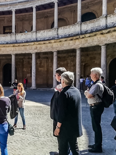 Visitors in the circular courtyard of the Alhambra's Nasrid Palaces during a guided tour.