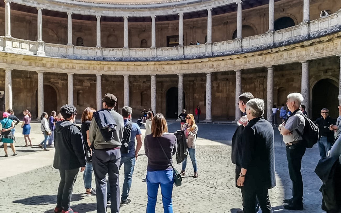 Visitors in the circular courtyard of the Alhambra's Nasrid Palaces during a guided tour.