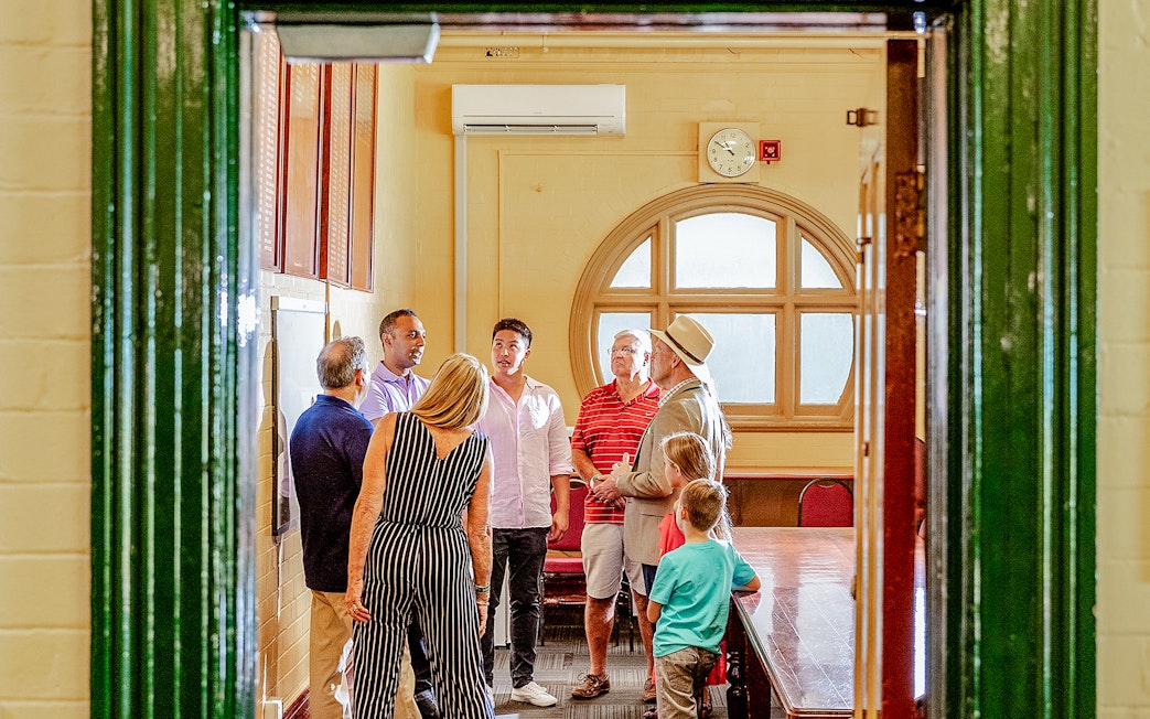Tour group with guide inside Sydney Cricket Ground meeting room.