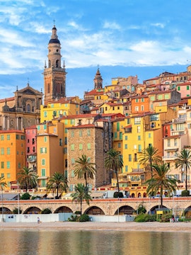 Colorful buildings and palm trees along the waterfront in Nice, France.