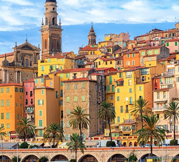 Colorful buildings and palm trees along the waterfront in Nice, France.