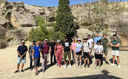 Group of tourists at Gobustan National Park, Baku, with rock formations in the background.
