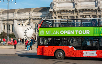 Milan hop-on hop-off tour bus near Central Station and apple sculpture.