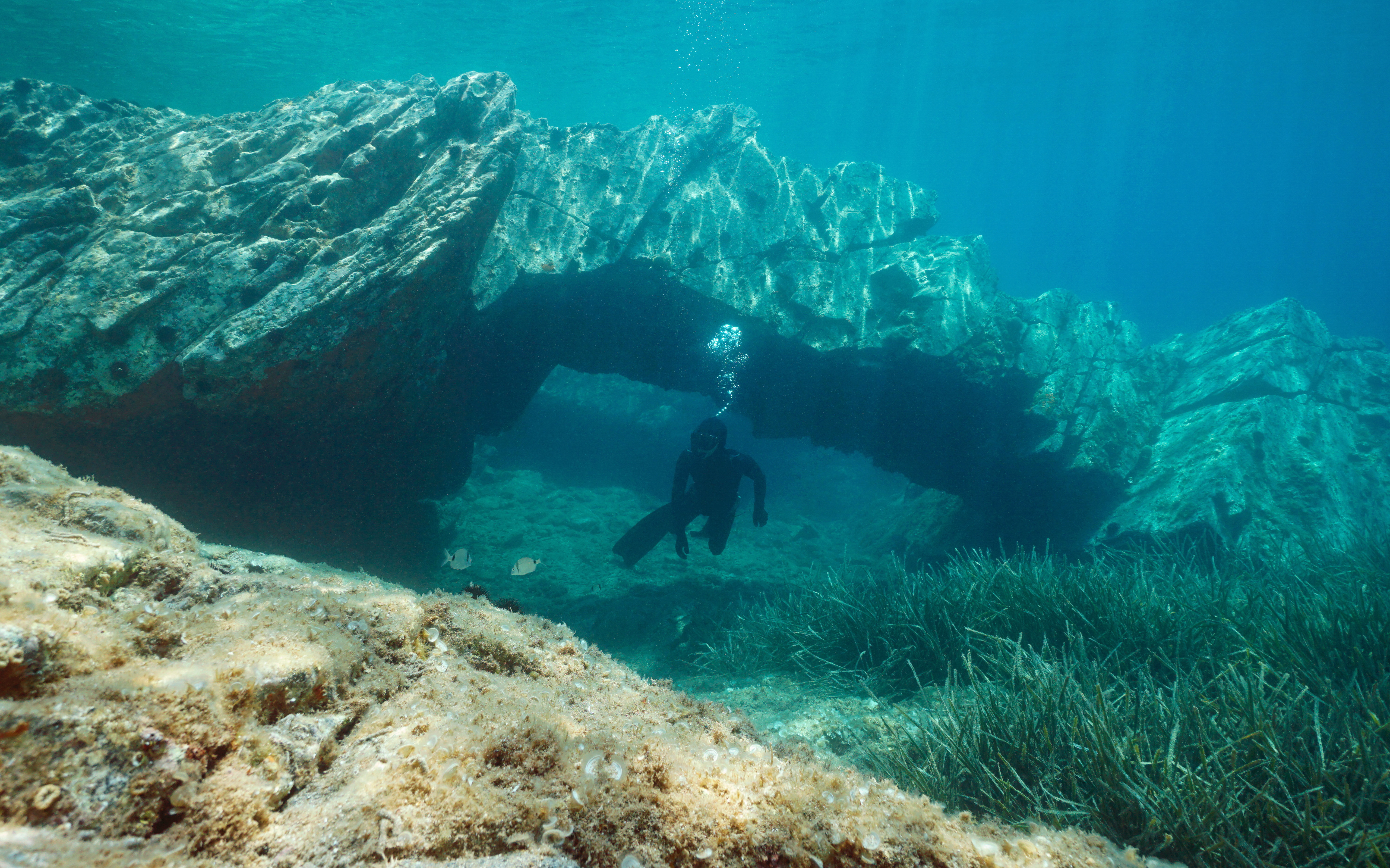 Man freediving near rocky underwater arch in Cap de Creus, Costa Brava, Spain.