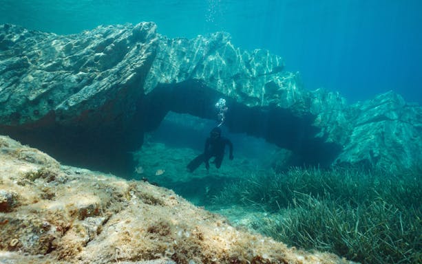 Man freediving near rocky underwater arch in Cap de Creus, Costa Brava, Spain.