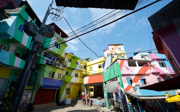 Colorful buildings in Favela Santa Marta, Rio de Janeiro, Brazil, with people walking below.