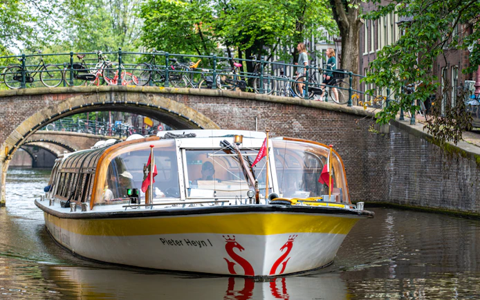 Canal boat cruising under a bridge in Amsterdam.