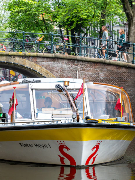 Canal boat cruising under a bridge in Amsterdam.