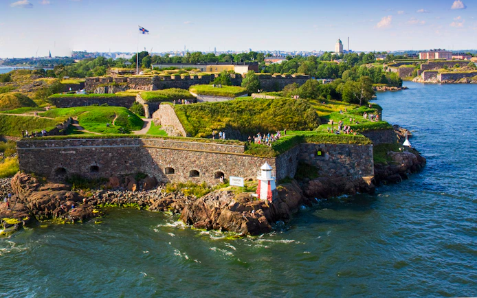 Suomenlinna sea fortress with visitors on grassy ramparts, Helsinki, Finland.