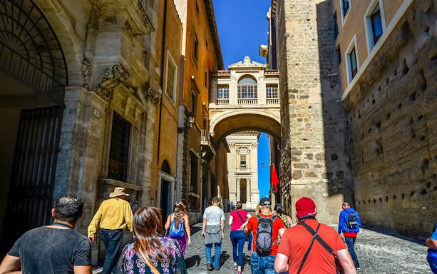 Tour group walking through historic archway in Rome on Christian relics tour.