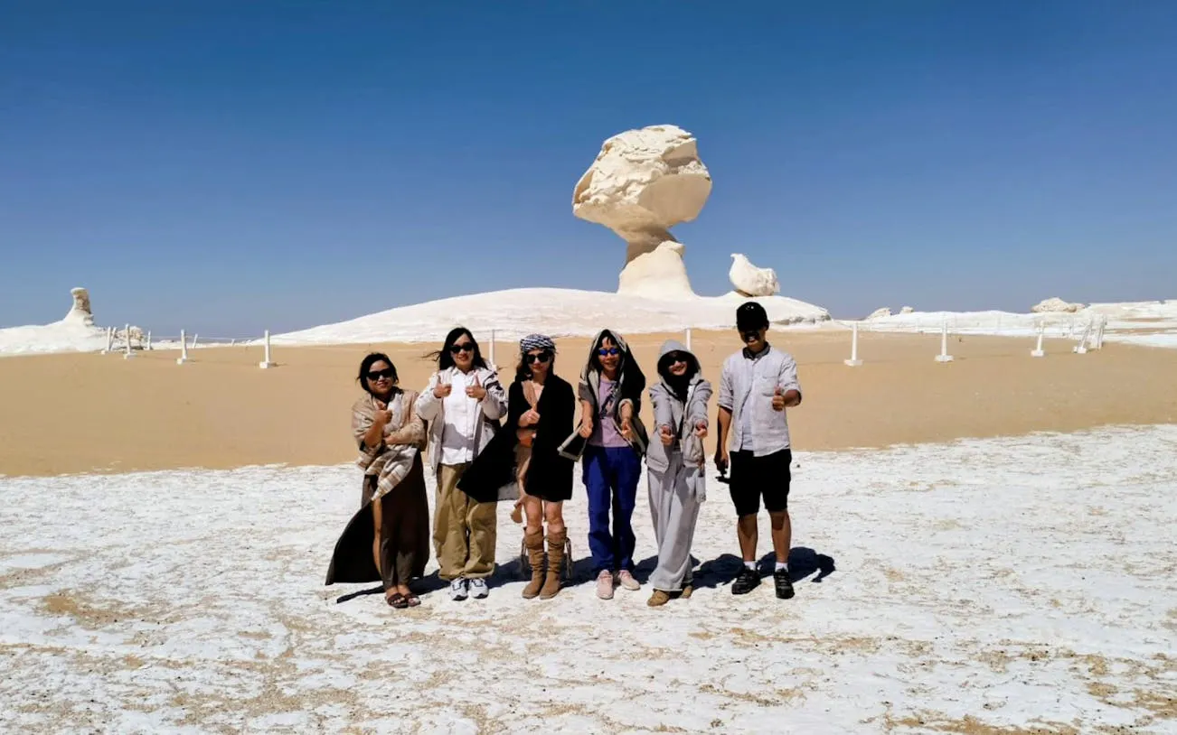 Group of tourists in the White Desert, Egypt, with unique rock formations in the background.