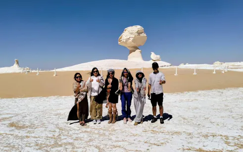 Group of tourists in the White Desert, Egypt, with unique rock formations in the background.