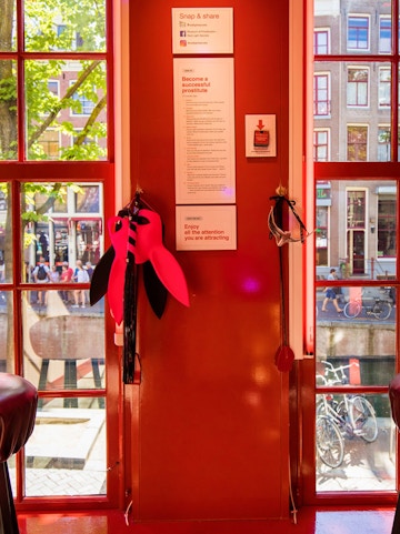 Red Light Secrets Museum interior with red walls, window view of Amsterdam street.