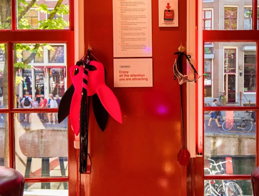 Red Light Secrets Museum interior with red walls, window view of Amsterdam street.