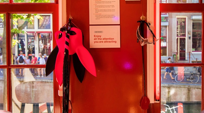 Red Light Secrets Museum interior with red walls, window view of Amsterdam street.