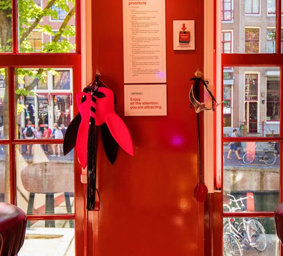 Red Light Secrets Museum interior with red walls, window view of Amsterdam street.