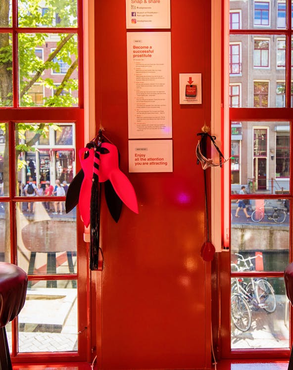 Red Light Secrets Museum interior with red walls, window view of Amsterdam street.