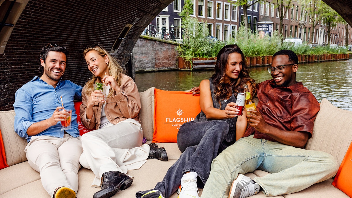 Guests enjoying drinks on a luxury open boat cruise in Amsterdam canal.