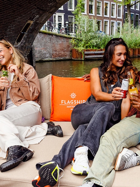 Guests enjoying drinks on a luxury open boat cruise in Amsterdam canal.