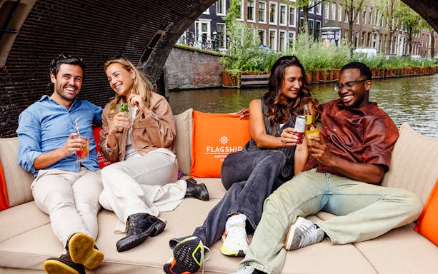 Guests enjoying drinks on a luxury open boat cruise in Amsterdam canal.