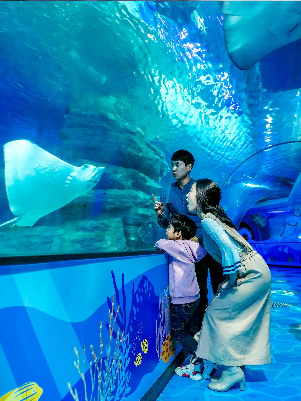 Family observing stingrays in underwater tunnel at SEA LIFE Busan Aquarium.
