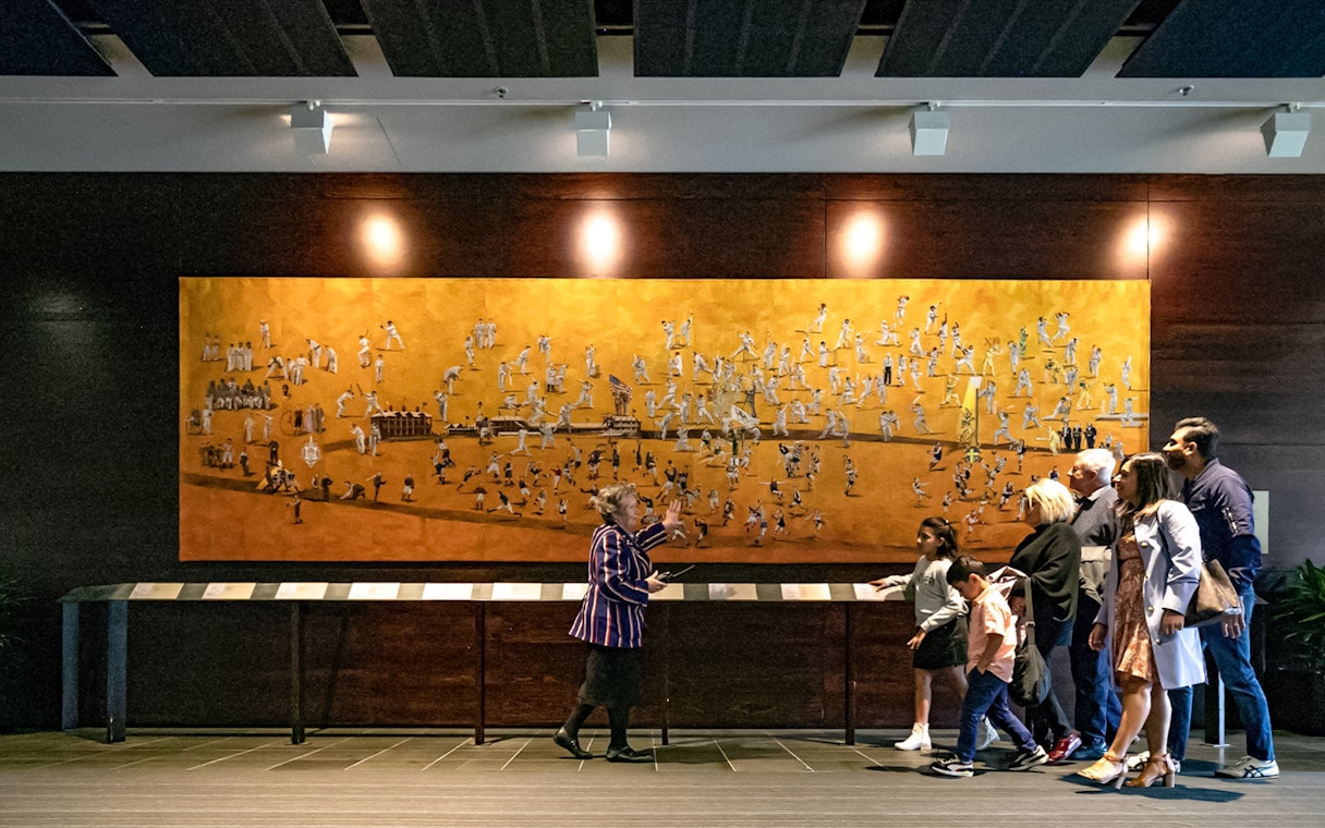 Tour group viewing artwork at Melbourne Cricket Ground during guided sports walking experience.