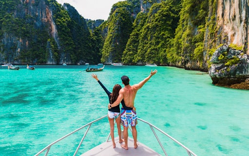 Couple on boat exploring Pileh Lagoon surrounded by cliffs and turquoise water.