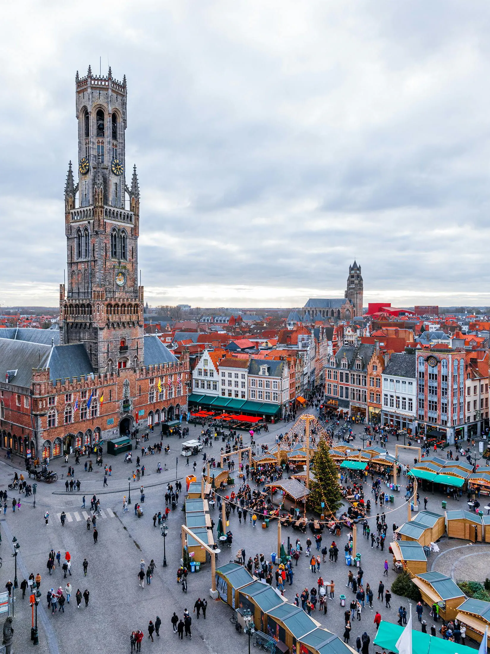 Cityscape of Bruges main square with Belfry Tower and market stalls.