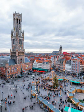 Cityscape of Bruges main square with Belfry Tower and market stalls.