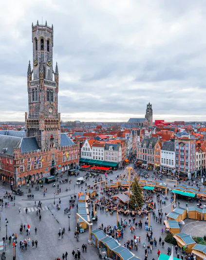Cityscape of Bruges main square with Belfry Tower and market stalls.