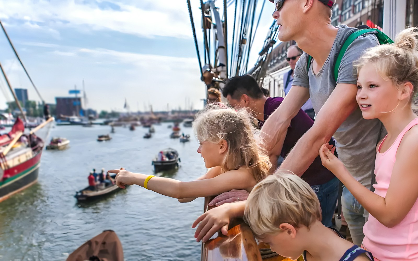 Tourists on a cruise ship enjoying Sail Amsterdam event with boats in the background.