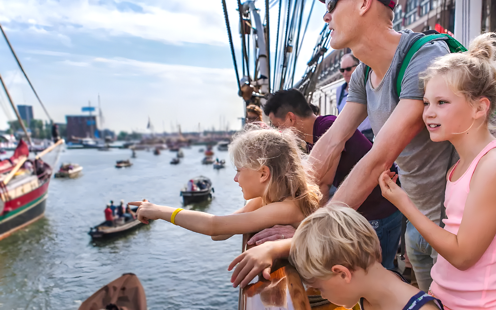 Tourists on a cruise ship enjoying Sail Amsterdam event with boats in the background.