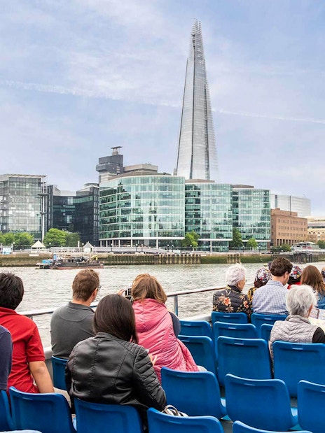 People on a Thames River cruise with views of The Shard and City Hall in London.