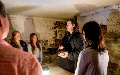 Guide explaining history to group during Port Arthur Ghost Tour in dimly lit stone room.