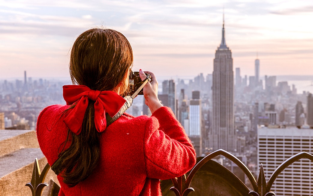 Visitor photographing Empire State Building from Top of the Rock, New York City.