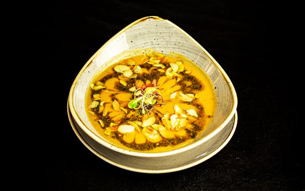 Bowl of soup garnished with sliced almonds and herbs on Danube River dinner cruise.