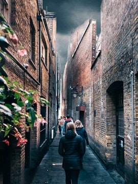 People walking through a narrow alley in London, reminiscent of Harry Potter film locations.