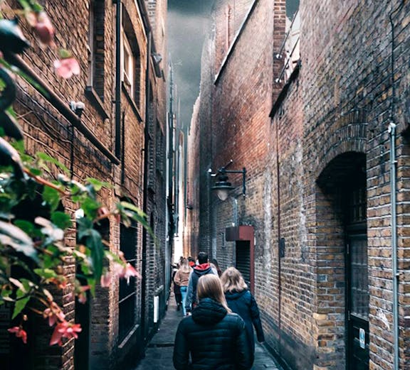 People walking through a narrow alley in London, reminiscent of Harry Potter film locations.